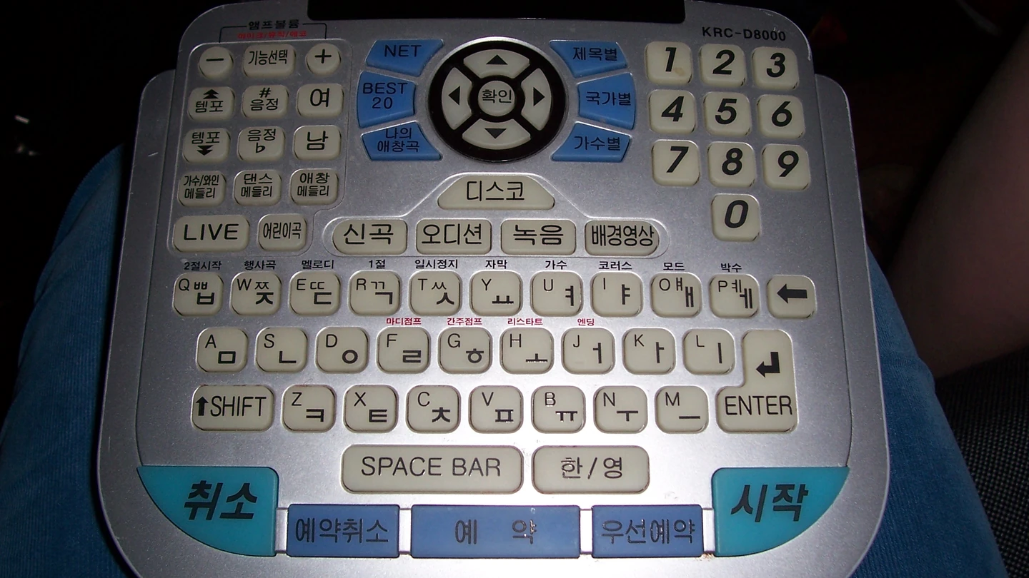 금영 노래방 리모컨. 번호 버튼과 한글 자판 위에 「멜로디」「코러스」「가수」 같은 작은 기능 이름이 인쇄돼 있다 (사진 Catherine, Flickr, CC BY 2.0)