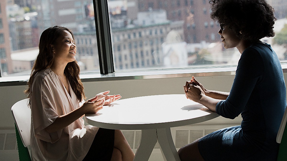 Two people sitting across from each other at a round table by a window